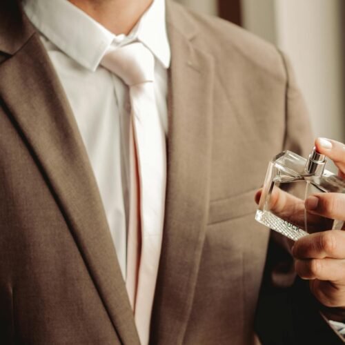 man wearing suit and necktie with perfume bottle